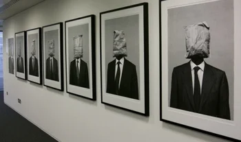 photographs on the wall of an office. The people have teabags for heads